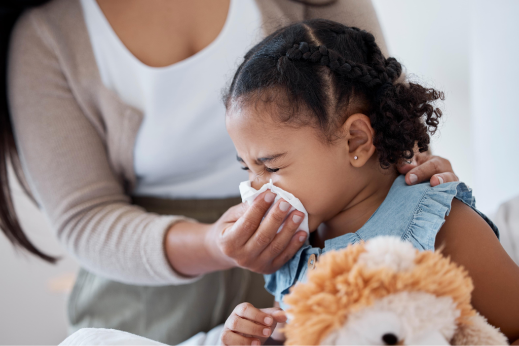 Child sneezing into a tissue due to cold symptoms.